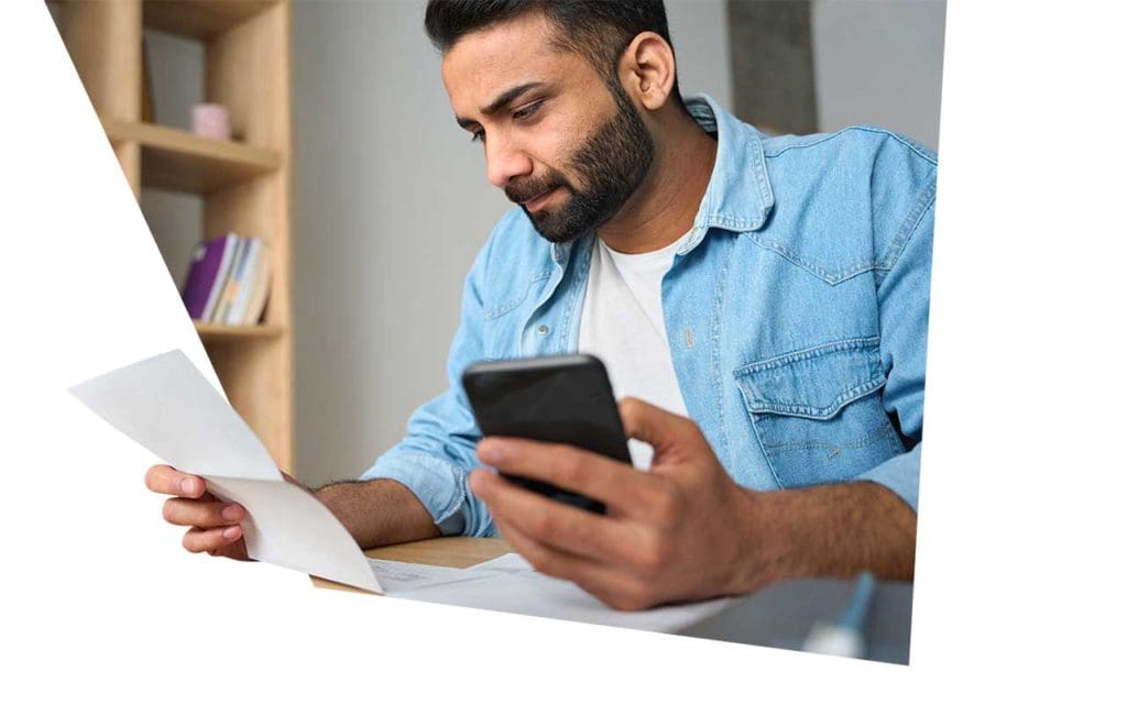 Homme sur son smartphone tenant un document